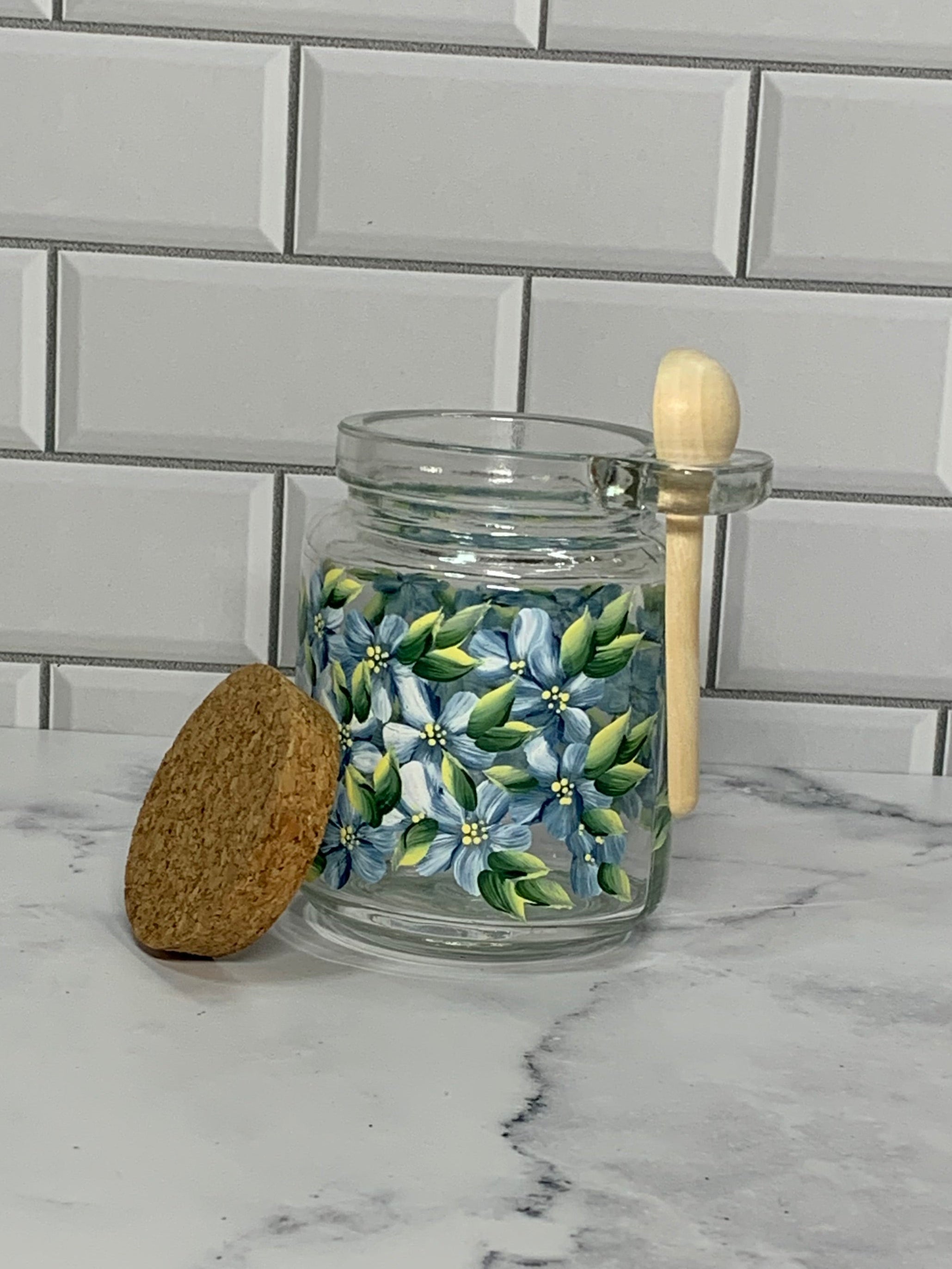 8oz glass jar with cork lid and bamboo spoon hand painted with blue flowers all around.
